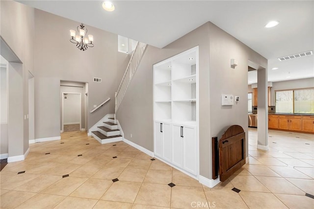 entrance foyer with a chandelier, visible vents, stairway, and light tile patterned floors