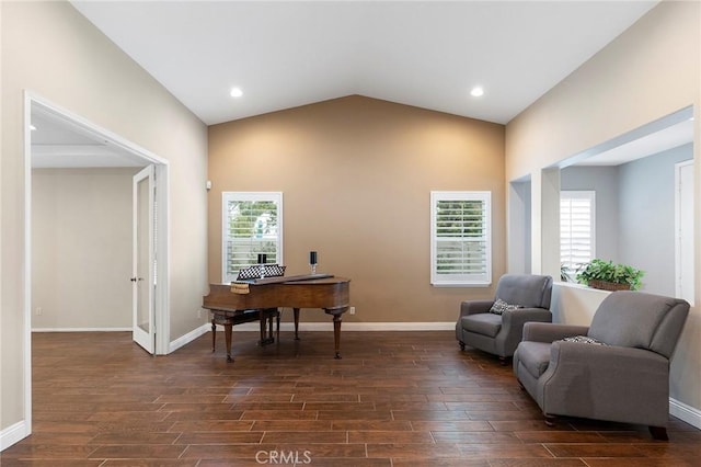 living area featuring a wealth of natural light, vaulted ceiling, dark wood finished floors, and baseboards