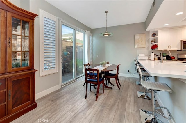 dining space featuring light wood finished floors, baseboards, and recessed lighting