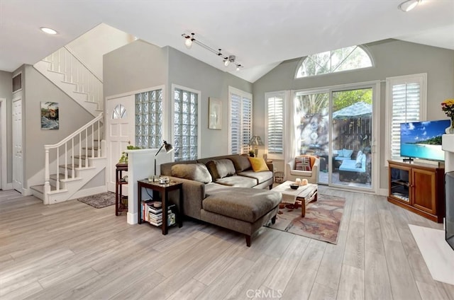 living room featuring lofted ceiling, visible vents, baseboards, stairs, and light wood-type flooring