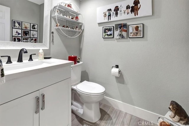 bathroom with vanity, wood finished floors, toilet, and baseboards