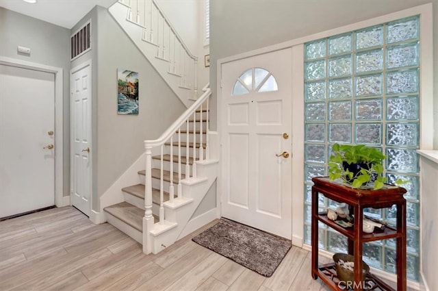 foyer featuring wood finish floors, visible vents, stairway, and baseboards