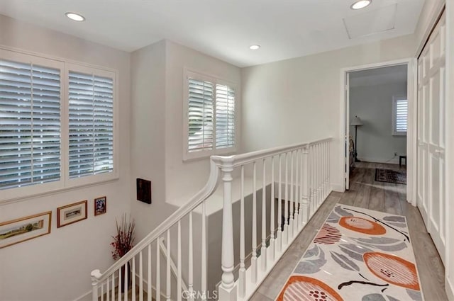 hall with recessed lighting, attic access, an upstairs landing, wood finished floors, and baseboards