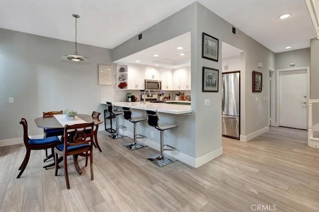 dining area featuring light wood-style floors, baseboards, and recessed lighting