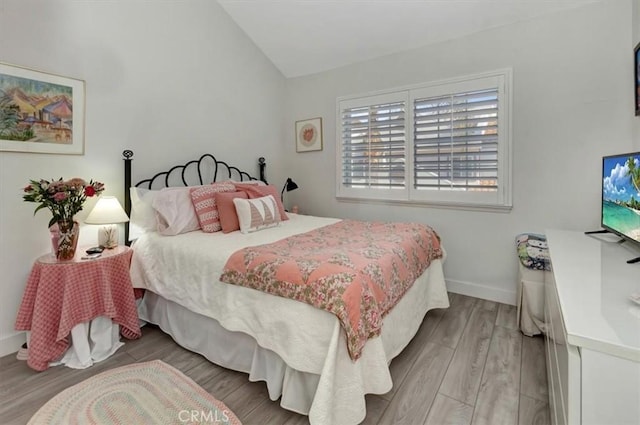 bedroom featuring lofted ceiling, baseboards, and wood finished floors