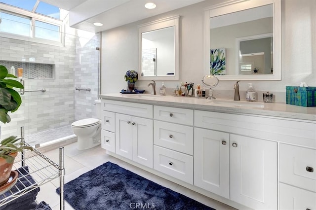 full bathroom with double vanity, a sink, toilet, and a shower stall