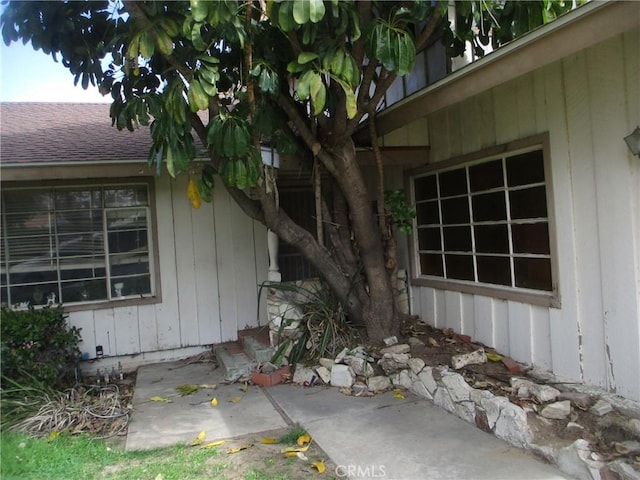 view of side of property featuring a shingled roof and a patio