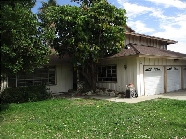 view of front of house featuring entry steps, an attached garage, a shingled roof, board and batten siding, and a front yard