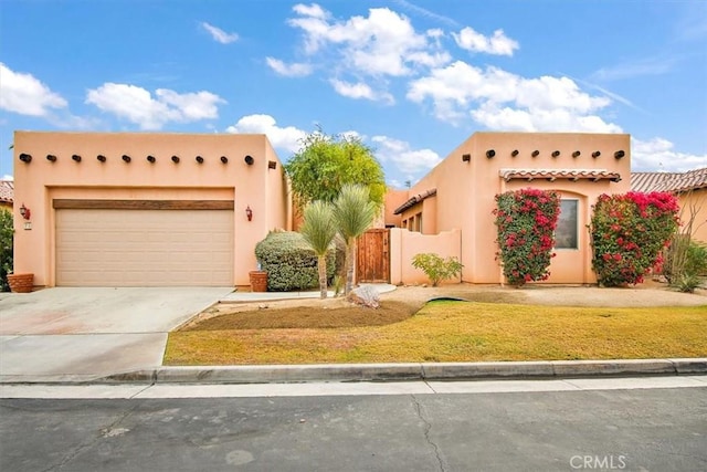 adobe home with driveway, a garage, a front lawn, and stucco siding