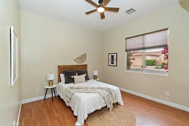 bedroom with ceiling fan, wood finished floors, visible vents, and baseboards