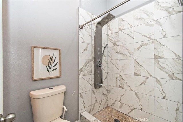 full bathroom featuring tiled shower and toilet