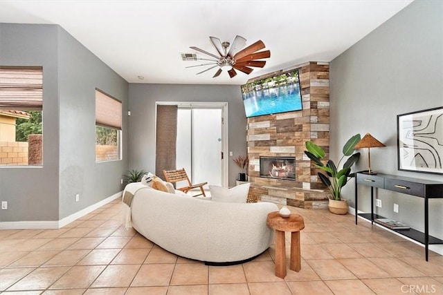 living room with a large fireplace, light tile patterned floors, baseboards, visible vents, and ceiling fan