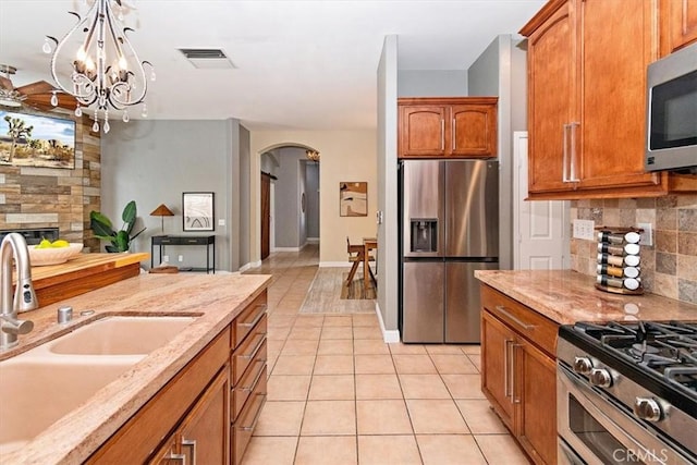 kitchen with light tile patterned floors, visible vents, arched walkways, stainless steel appliances, and backsplash