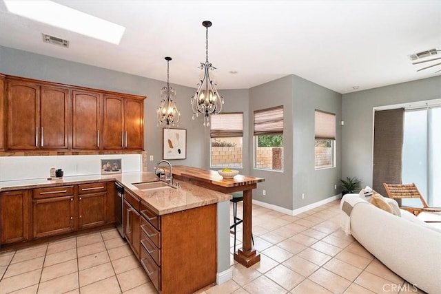 kitchen with a peninsula, a breakfast bar, a sink, visible vents, and stainless steel dishwasher