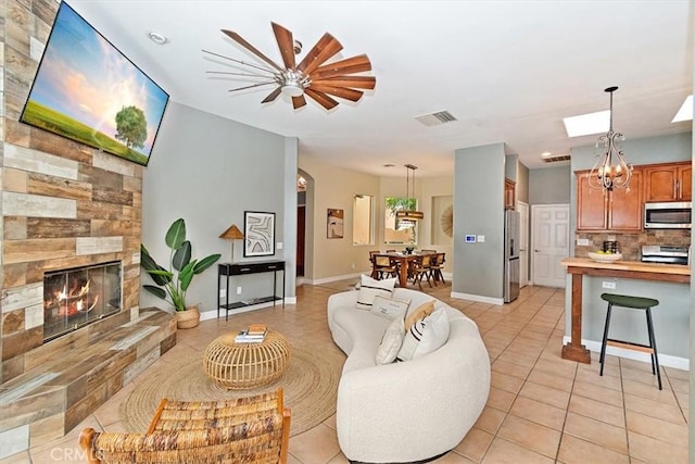 living room with light tile patterned floors, a stone fireplace, visible vents, and baseboards