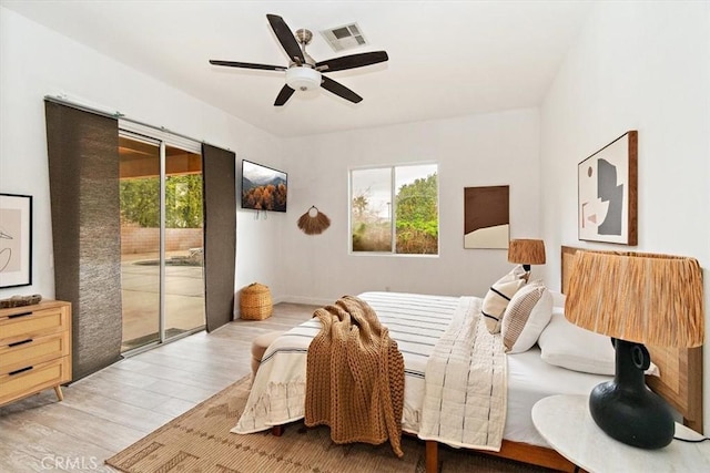 bedroom with multiple windows, wood finished floors, visible vents, and access to exterior