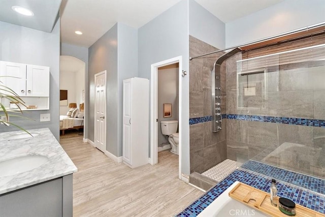 ensuite bathroom with ensuite bathroom, wood finished floors, a tile shower, and toilet