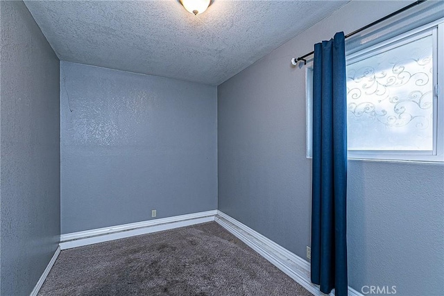 carpeted spare room with baseboards, a textured ceiling, and a textured wall