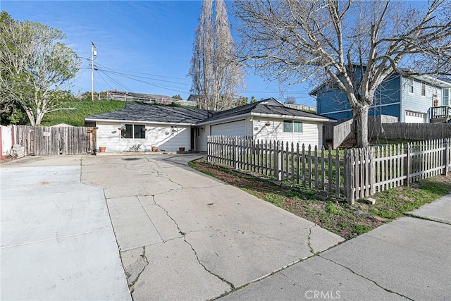 view of front of home with driveway, a fenced front yard, and an attached garage