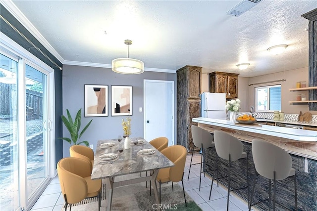 dining area featuring light tile patterned floors, a textured ceiling, visible vents, and crown molding