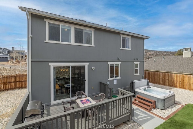 rear view of property featuring a fire pit, a patio, fence, and a hot tub