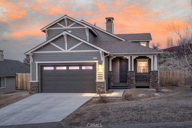 craftsman-style house with a shingled roof, covered porch, fence, stone siding, and driveway