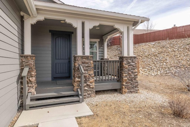 doorway to property featuring a porch and fence