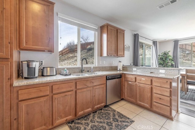 kitchen featuring a peninsula, a sink, visible vents, stainless steel dishwasher, and brown cabinetry