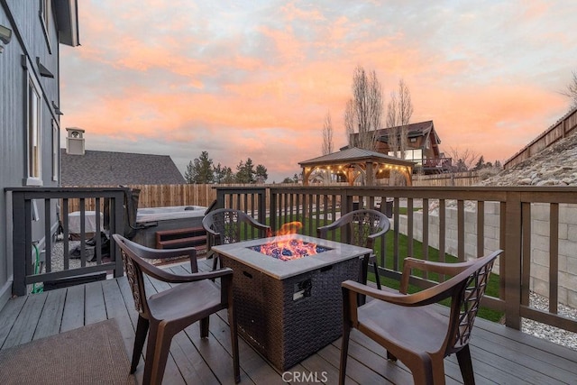 wooden terrace featuring an outdoor fire pit, fence, and a gazebo