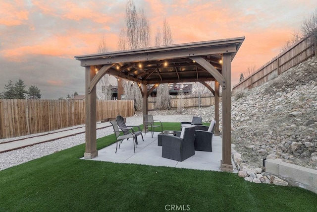 patio terrace at dusk with a yard, a gazebo, a fenced backyard, and an outdoor living space