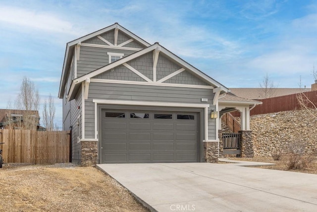 craftsman-style home with a garage, stone siding, driveway, and fence