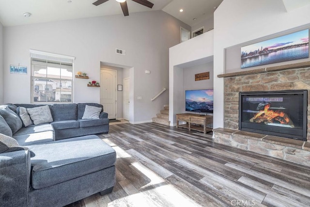 living room featuring a fireplace, visible vents, stairway, wood finished floors, and baseboards