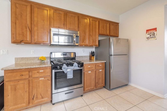 kitchen with light stone countertops, appliances with stainless steel finishes, and brown cabinets