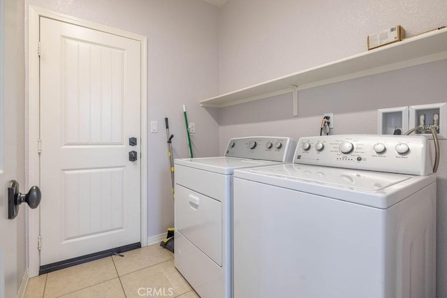 clothes washing area with laundry area, light tile patterned floors, baseboards, visible vents, and washing machine and clothes dryer