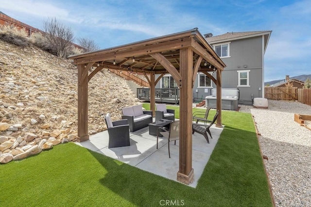 view of patio featuring outdoor lounge area, fence, a hot tub, and a gazebo