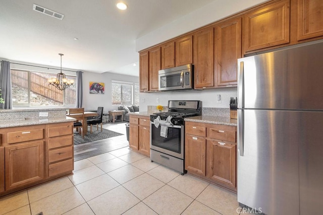 kitchen featuring brown cabinets, visible vents, an inviting chandelier, appliances with stainless steel finishes, and light tile patterned flooring