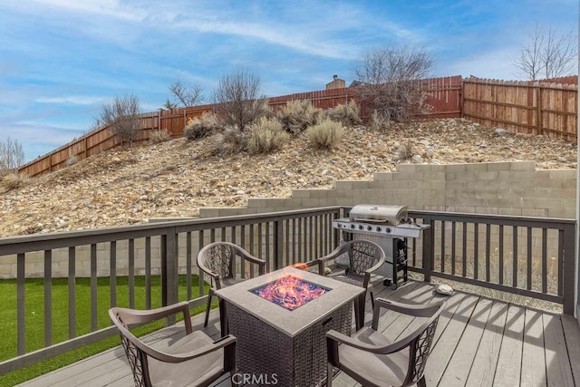 wooden terrace with a fenced backyard, a lawn, a fire pit, and area for grilling