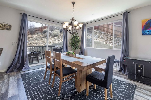 dining area with baseboards, an inviting chandelier, and wood finished floors