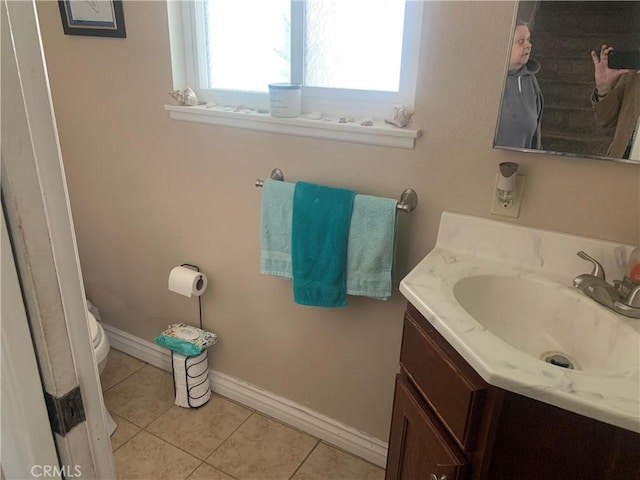 bathroom featuring toilet, tile patterned flooring, baseboards, and vanity