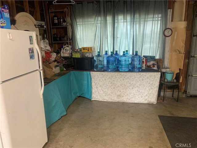 kitchen featuring concrete flooring and freestanding refrigerator