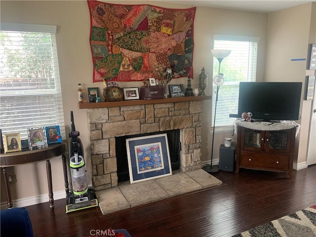 living area with a fireplace, baseboards, and wood finished floors