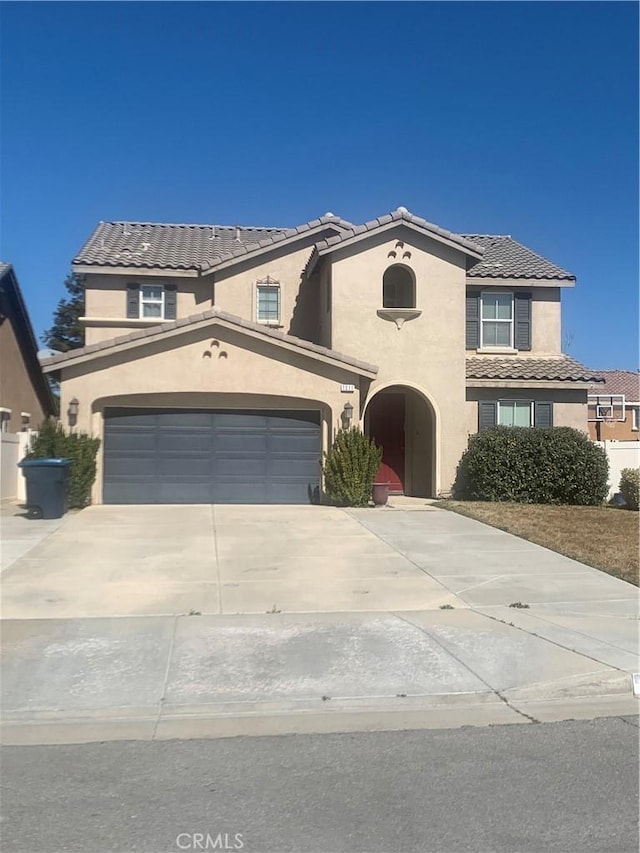 view of front of home featuring a garage, a tiled roof, concrete driveway, and stucco siding