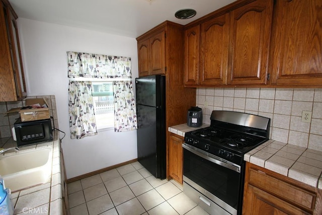 kitchen with tile countertops, black appliances, a sink, and decorative backsplash