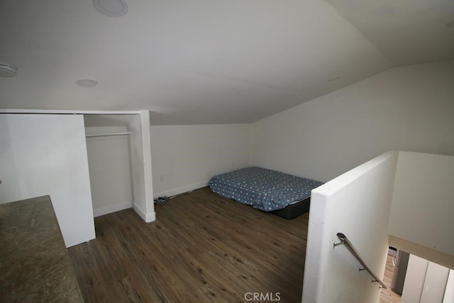 unfurnished bedroom with lofted ceiling, a closet, baseboards, and wood finished floors