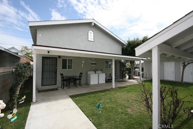 rear view of house with a lawn, fence, washer and dryer, a patio area, and stucco siding