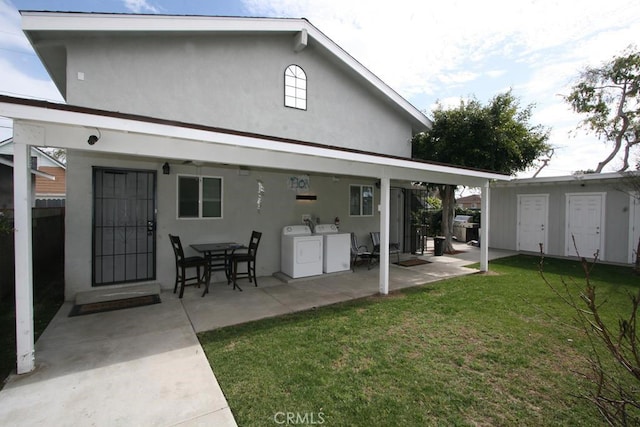 back of property featuring a yard, a patio, stucco siding, separate washer and dryer, and an outdoor structure