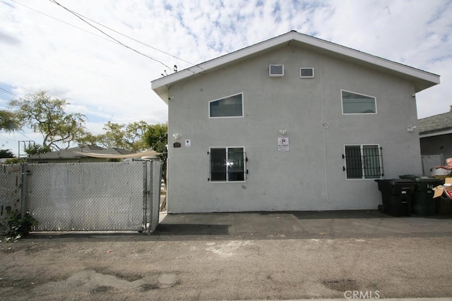 view of side of property featuring fence, a gate, and stucco siding