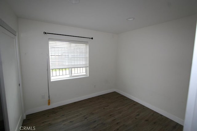 unfurnished room with dark wood finished floors and baseboards