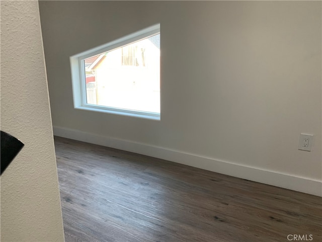 empty room featuring dark wood-type flooring and baseboards