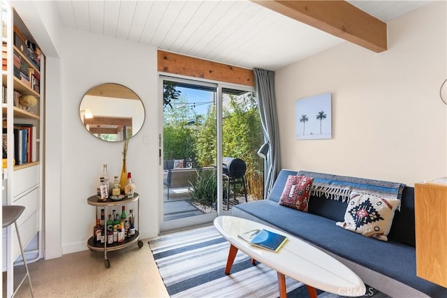 living area featuring beamed ceiling, wooden ceiling, and baseboards